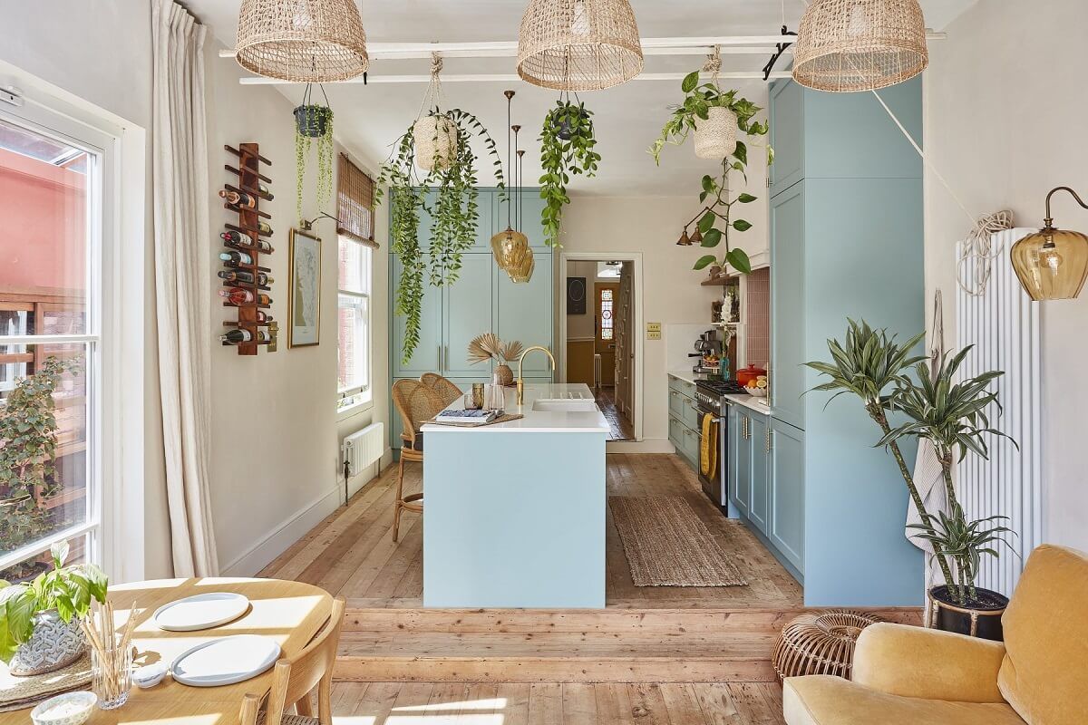 Una casa con cocina azul y una bañera vintage rosa en el dormitorio